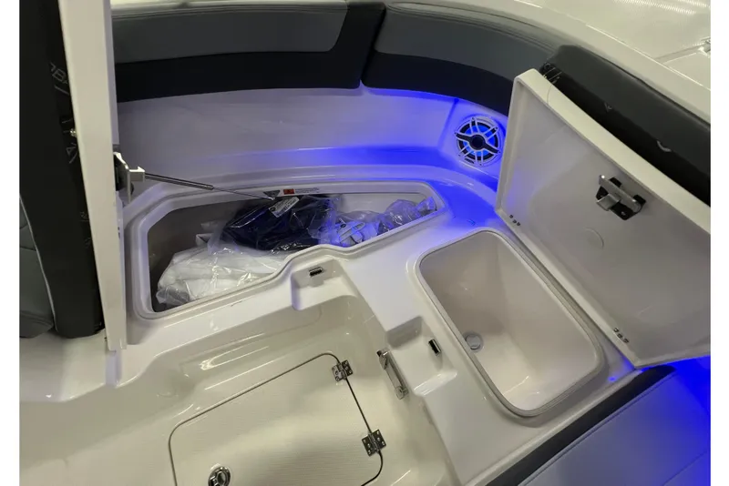 Slide: The Image of 2026 Robalo R257 Dual Console boat interior with storage compartments and blue LED lighting. - 23