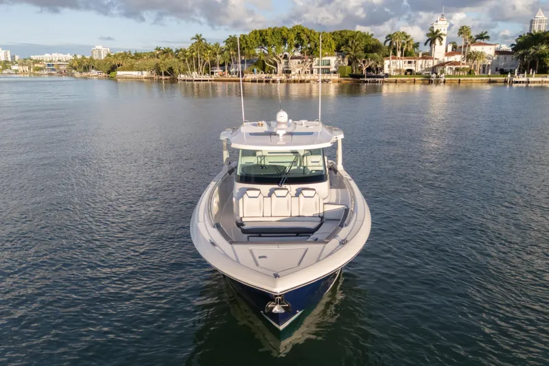 Slide: The Image of 2020 Tiara Yachts 43 LS on calm water, surrounded by lush greenery and luxury homes. - 6