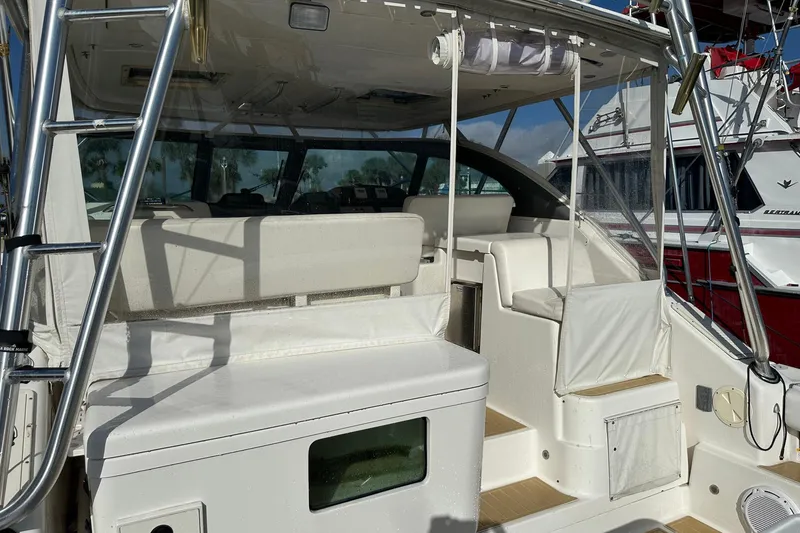 Slide: The Image of 2004 Pursuit 3800 Express boat interior with seating and ladder, docked beside another vessel. - 17