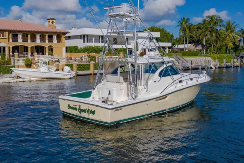 Slide: The Image of 2004 Pursuit 3800 Express boat docked near luxury waterfront homes. - 3