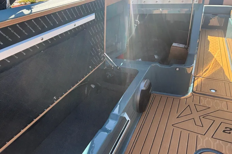 Slide: The Image of 2026 MasterCraft XT22 boat interior with open storage compartment and sunlit deck. - 13