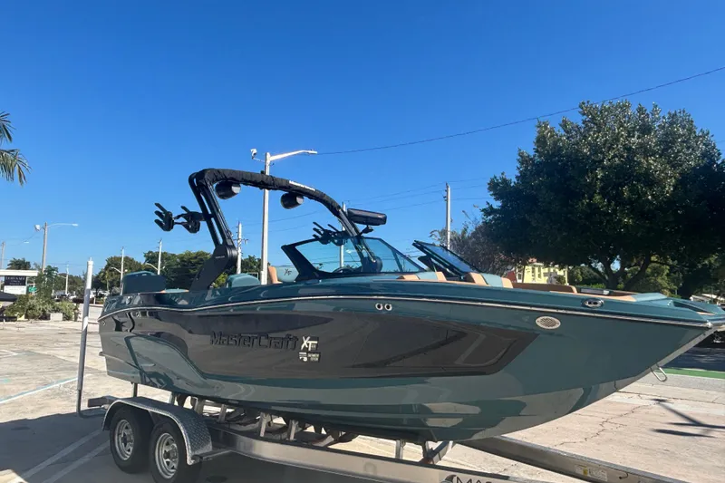 Slide: The Image of 2026 MasterCraft XT22 boat on trailer under clear blue sky. - 3