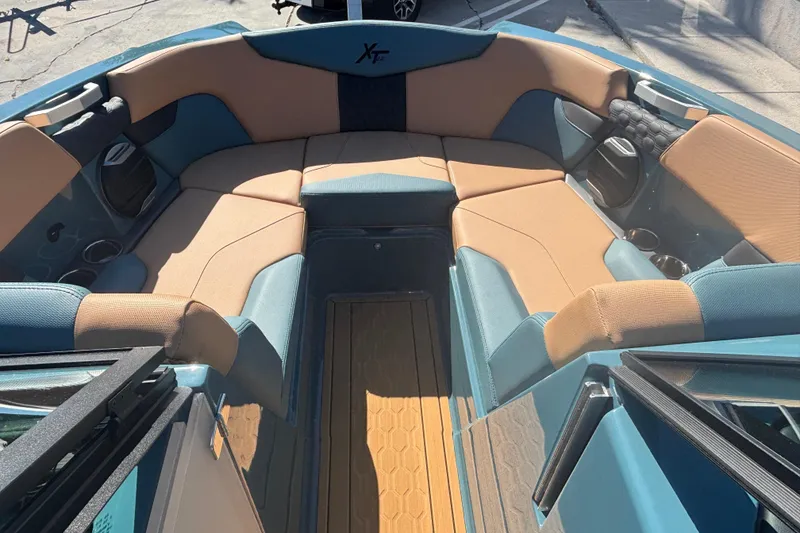 Slide: The Image of 2026 MasterCraft XT22 boat interior with tan and blue seating, cup holders, and speakers. - 9