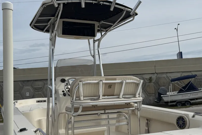 Slide: The Image of 2015 SeaChaser 23LX boat with T-top and console, docked near a concrete wall. - 10