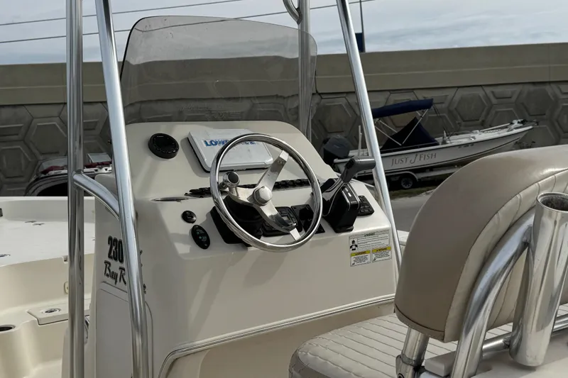Slide: The Image of 2015 SeaChaser 23LX boat console with steering wheel and controls, docked near other boats. - 11