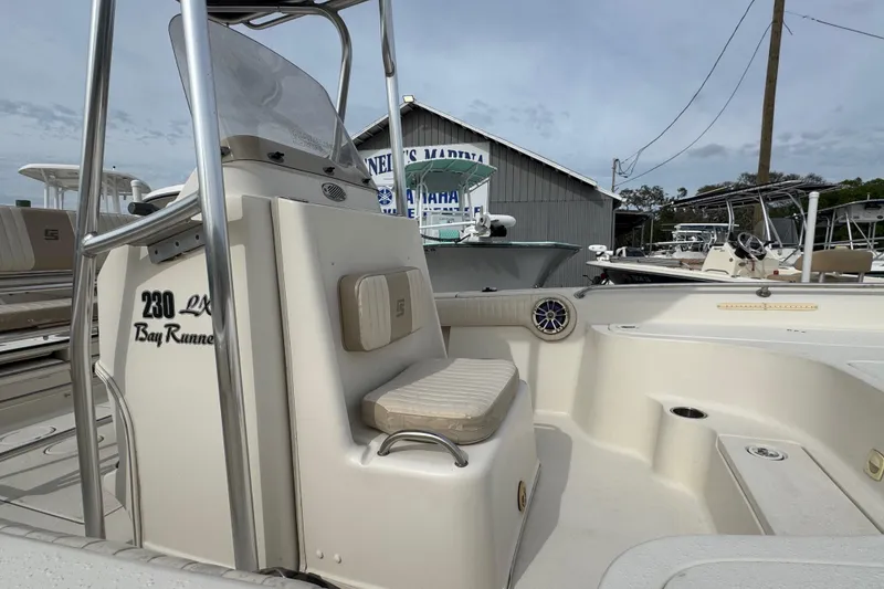 Slide: The Image of 2015 SeaChaser 23LX Bay Runner boat interior with seating and console, docked at marina. - 8
