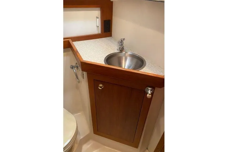 Slide: The Image of 2000 Mainship Pilot 34 Sedan bathroom with sink, wooden cabinet, and compact design. - 15