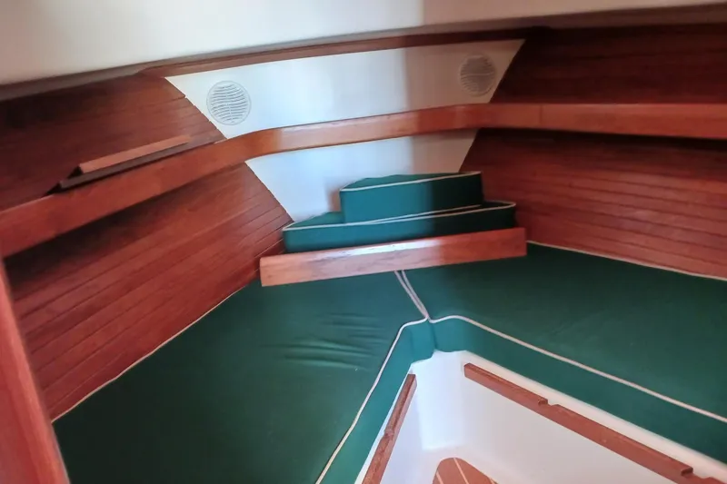 Slide: The Image of Interior of 2000 Mainship Pilot 34 Sedan with green cushions and wooden paneling. - 7