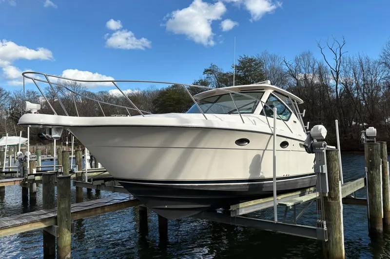 Slide: The Image of 2008 Tiara Yachts 3000 Open on lift, docked by a serene waterfront. - 2