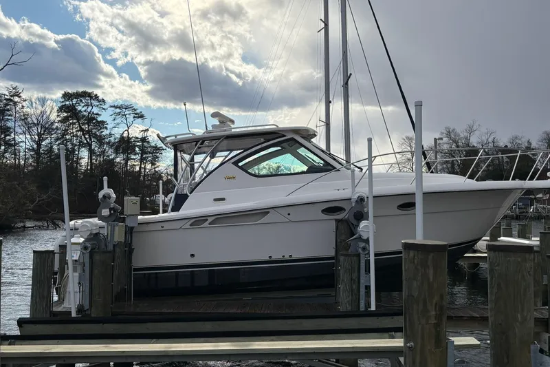 Slide: The Image of 2008 Tiara Yachts 3000 Open docked, surrounded by trees and cloudy sky. - 5