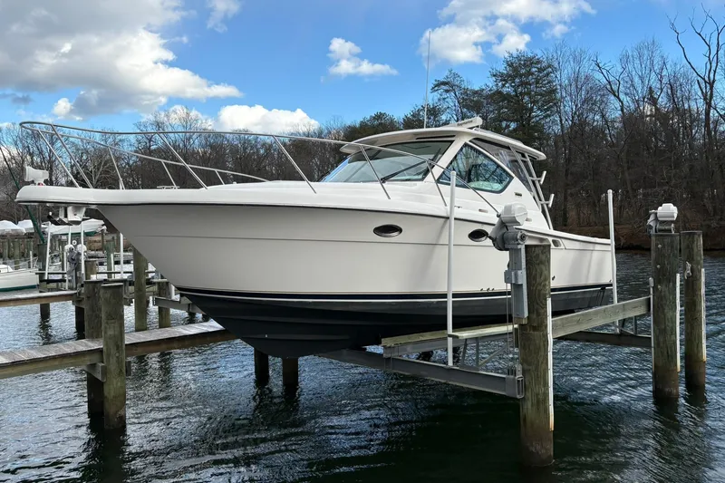 Slide: The Image of 2008 Tiara Yachts 3000 Open on lift, docked by a serene waterfront. - 7