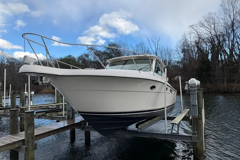 Slide: The Image of 2008 Tiara Yachts 3000 Open on a lift at a dock, under a cloudy sky. - 9