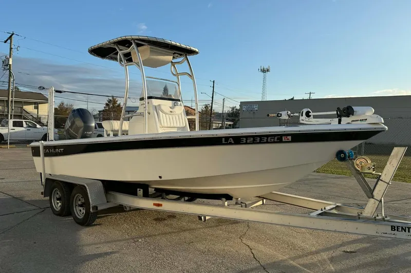 Slide: The Image of 2013 Sea Hunt XP 21 boat on trailer, parked outdoors under clear sky. - 2
