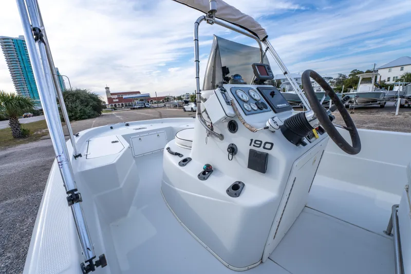 Slide: The Image of 2002 ProMaster 190 BAY boat interior with steering wheel and seating, parked near other boats. - 16