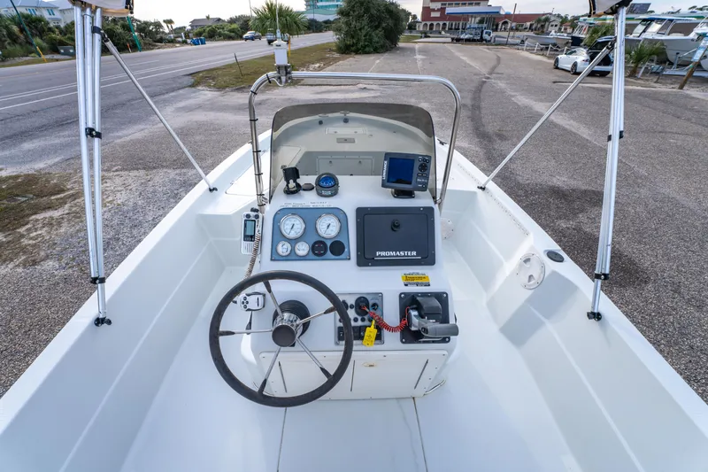 Slide: The Image of 2002 ProMaster 190 BAY boat interior with steering console and seating, parked outdoors. - 20
