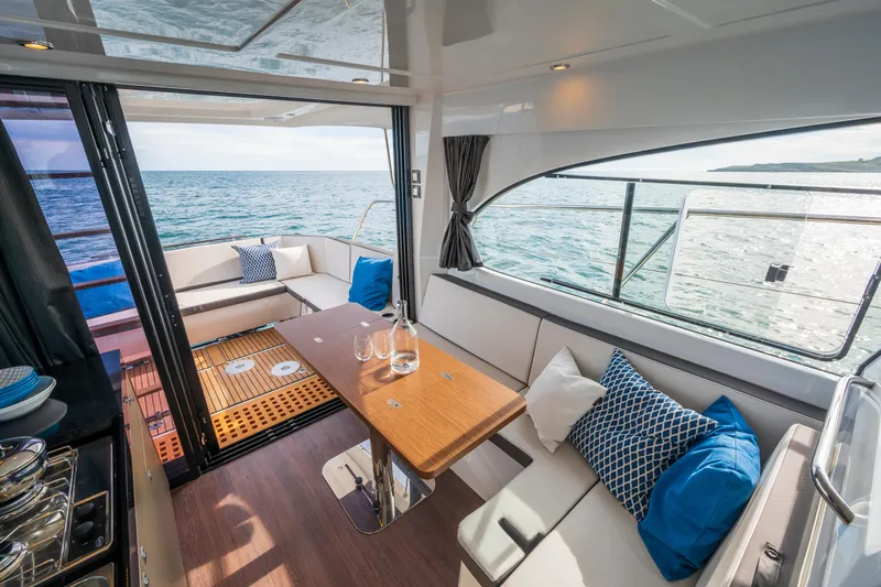 Slide: The Image of Interior of 2026 Beneteau Antares 11 Coupe with ocean view, featuring elegant seating and table. - 11