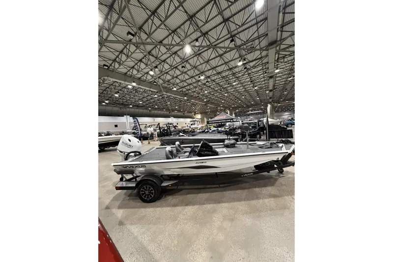Slide: The Image of 2026 Vexus Defender 189 boat displayed in a spacious indoor showroom. - 1