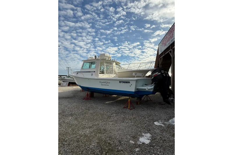 The Image of 2007 Steiger Craft 26 Miami boat on stands, under a partly cloudy sky. - 0