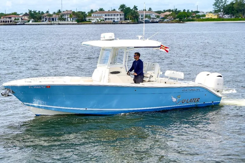 The Image of 2020 Cobia 262 Center Console boat cruising on water with a person at the helm. - 0