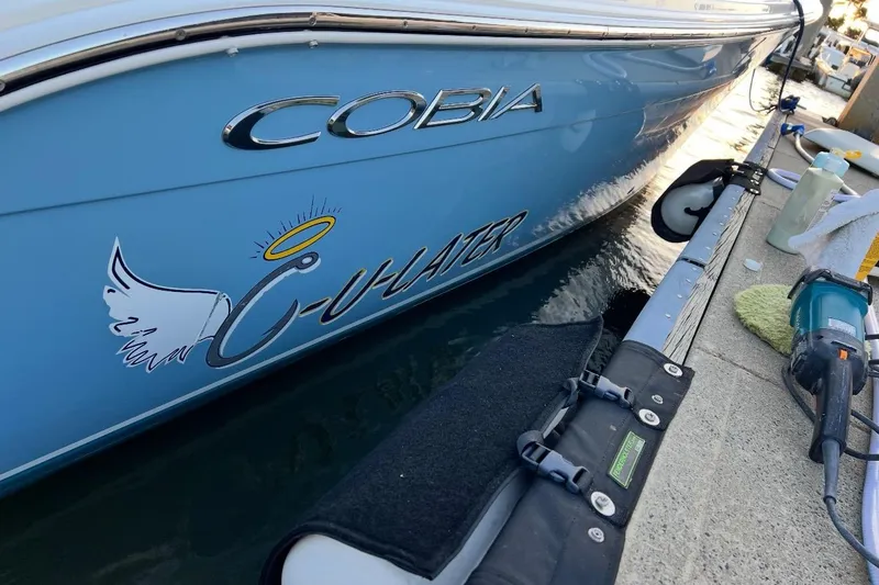 Slide: The Image of 2020 Cobia 262 Center Console boat docked, featuring custom "C-Water" decal. - 18
