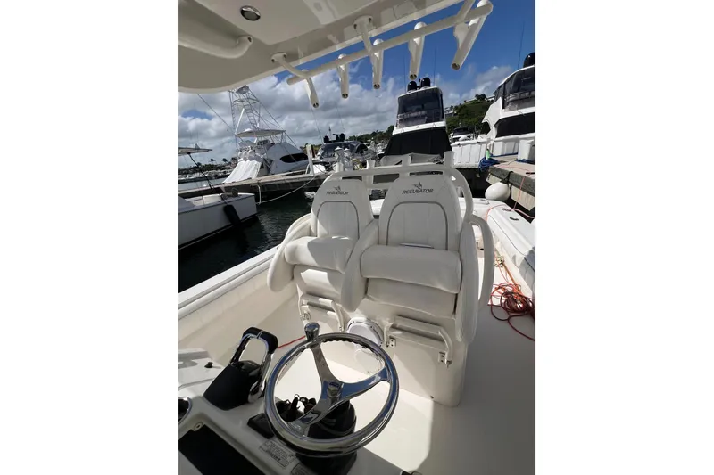 Slide: The Image of 2016 Regulator 34 Center Console boat interior with helm and seating at marina. - 13