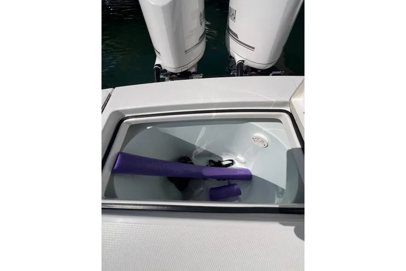 Slide: The Image of 2016 Regulator 34 Center Console boat storage compartment with purple pool noodles. - 29