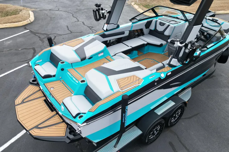 Slide: The Image of 2022 Nautique Super Air Nautique G21 boat with teal and gray interior, parked on a trailer. - 17