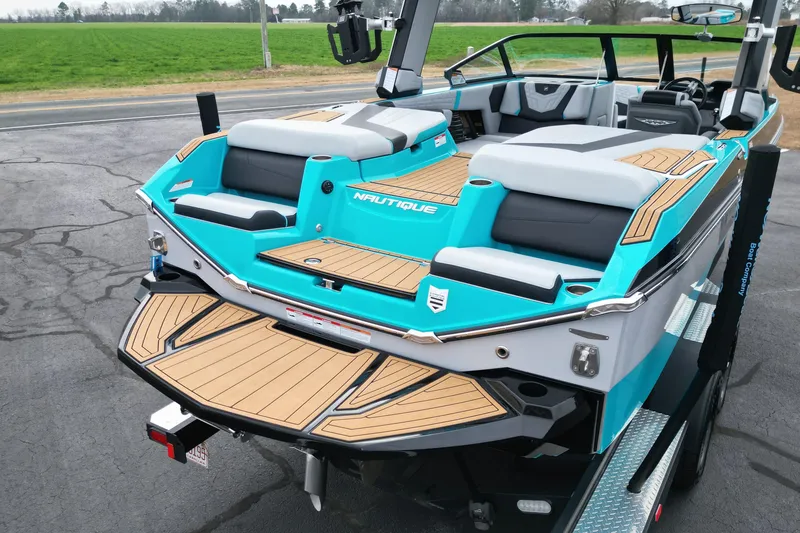 Slide: The Image of 2022 Nautique Super Air Nautique G21 boat with teal and gray seating, parked on a trailer. - 18