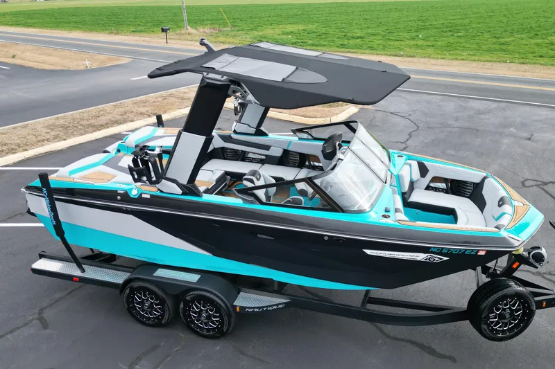 Slide: The Image of 2022 Nautique Super Air Nautique G21 boat on trailer, vibrant teal and black design. - 8
