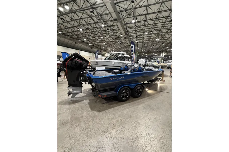 Slide: The Image of 2026 Vexus AVX 1985s boat displayed indoors, featuring a sleek blue design and powerful outboard motor. - 3