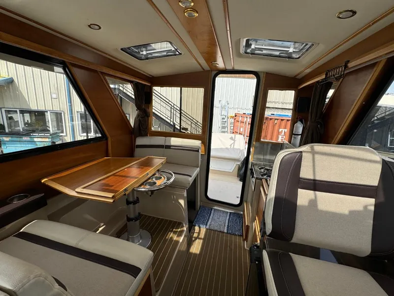 Slide: The Image of Interior of 2015 Cutwater C-26 boat, featuring seating, table, and windows. - 11