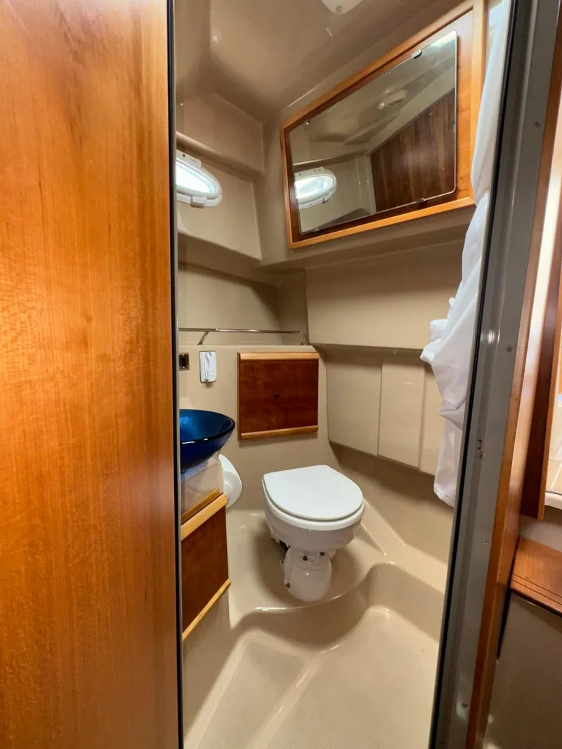 Slide: The Image of 2015 Cutwater C-26 boat bathroom with toilet, sink, mirror, and wooden cabinetry. - 25