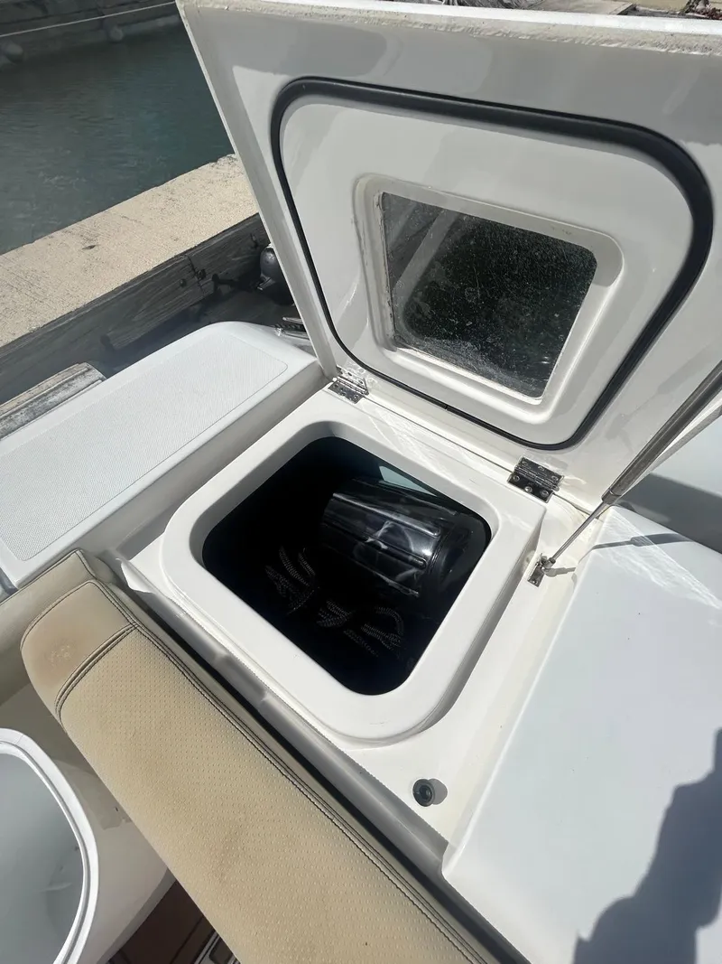 Slide: The Image of 2019 Pursuit OS 385 Offshore boat storage compartment with open hatch, dockside view. - 11