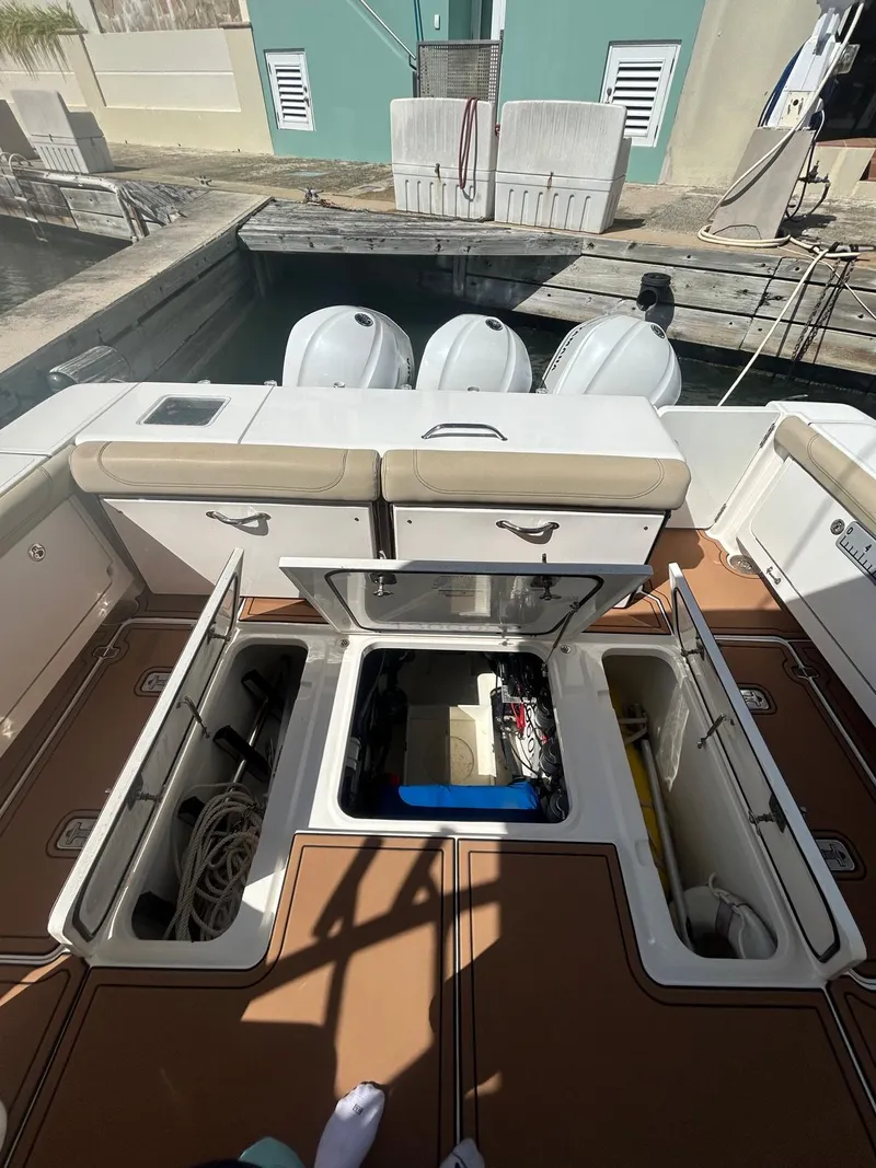 Slide: The Image of 2019 Pursuit OS 385 Offshore boat with open storage compartments and triple outboard engines. - 12