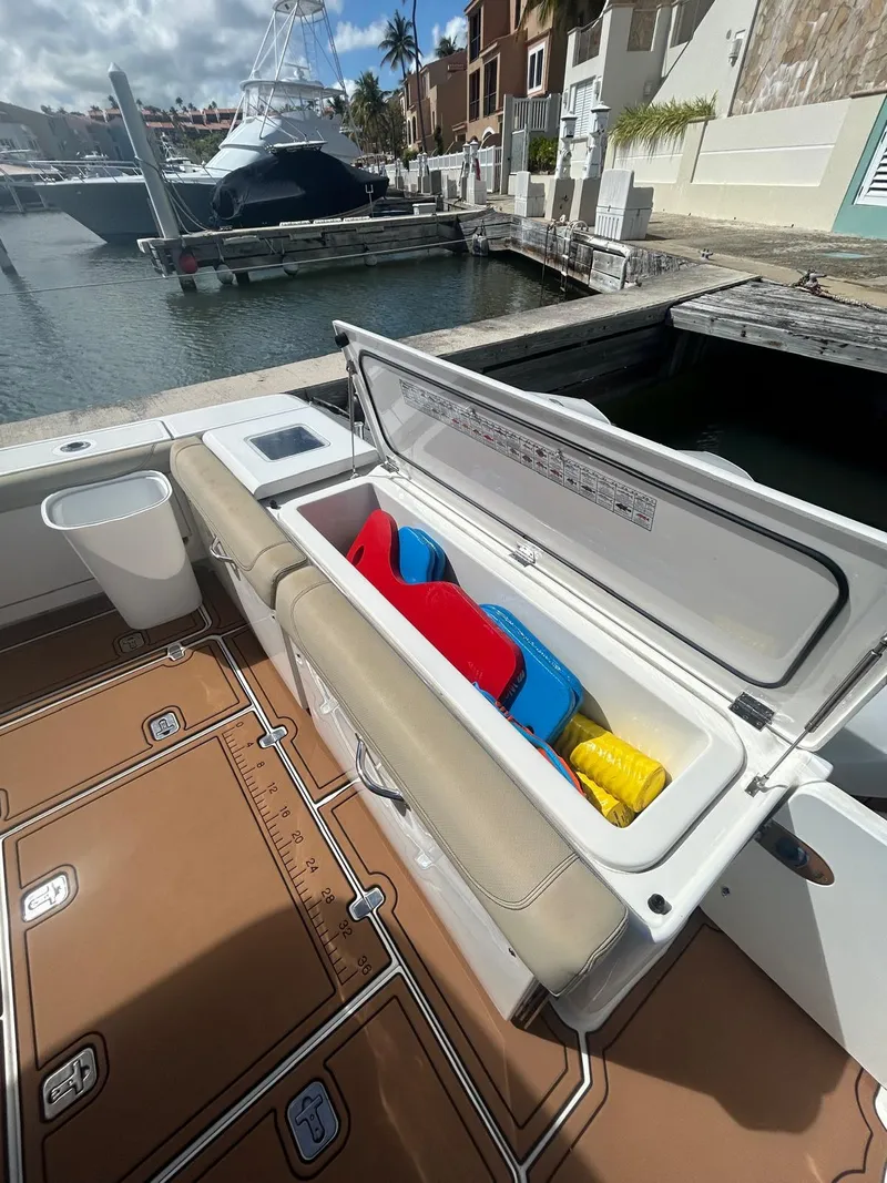 Slide: The Image of 2019 Pursuit OS 385 Offshore boat with open storage compartment at marina. - 13