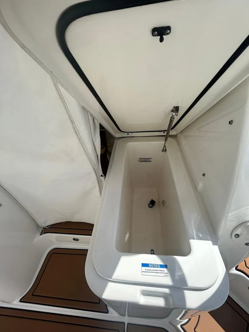 Slide: The Image of 2019 Pursuit OS 385 Offshore boat storage compartment, open lid, white interior. - 14