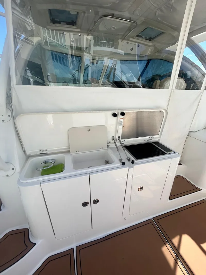 Slide: The Image of 2019 Pursuit OS 385 Offshore boat interior with kitchenette and sink. - 17