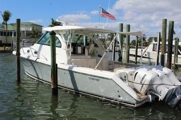 Slide: The Image of 2019 Pursuit OS 385 Offshore boat docked, featuring triple outboard engines and a sleek design. - 2