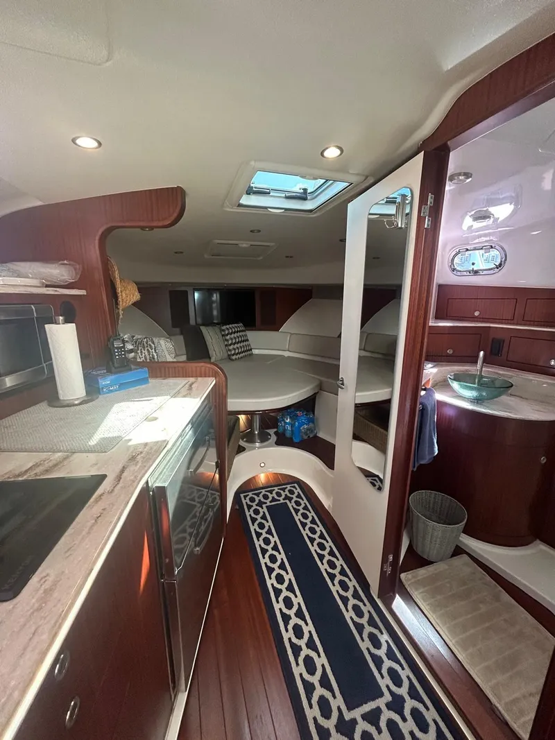 Slide: The Image of 2019 Pursuit OS 385 Offshore interior with kitchen, seating, and bathroom. Luxurious wood finish. - 25