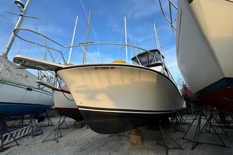 The Image of 1990 Luhrs 320 Tournament boat on stands, surrounded by other vessels, under a clear sky. - 0