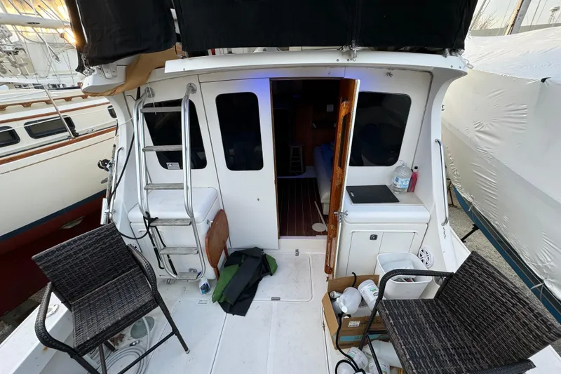 Slide: The Image of 1990 Luhrs 320 Tournament boat deck with chairs and ladder, docked beside other boats. - 14