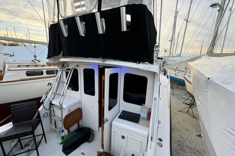 Slide: The Image of 1990 Luhrs 320 Tournament boat docked, featuring a ladder and covered upper deck. - 2