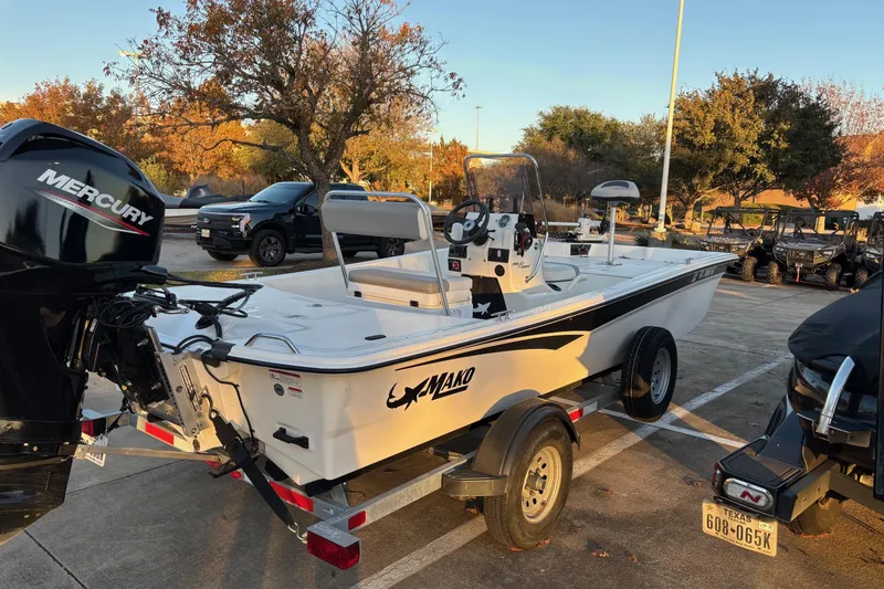 Slide: The Image of 2022 Mako Pro Skiff 17 CC boat on trailer, parked outdoors with trees in background. - 1