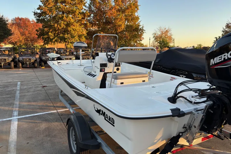 Slide: The Image of 2022 Mako Pro Skiff 17 CC boat on trailer, parked outdoors with trees in background. - 2