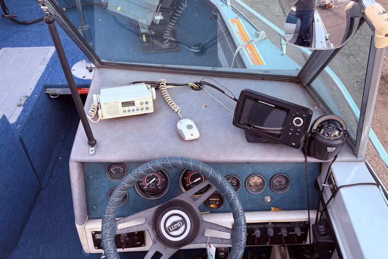 Slide: The Image of 1988 Lund boat dashboard with steering wheel, gauges, radio, and navigation equipment. - 15