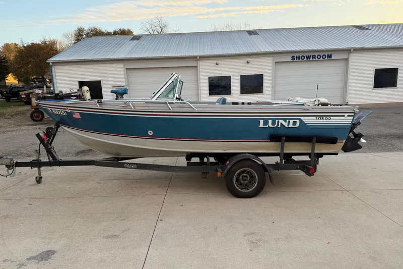 Slide: The Image of 1988 Lund boat on trailer outside showroom, blue and white design. - 4