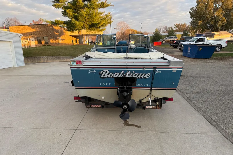 Slide: The Image of 1988 Lund boat named "Boat-tique" parked outdoors, featuring a blue exterior. - 6