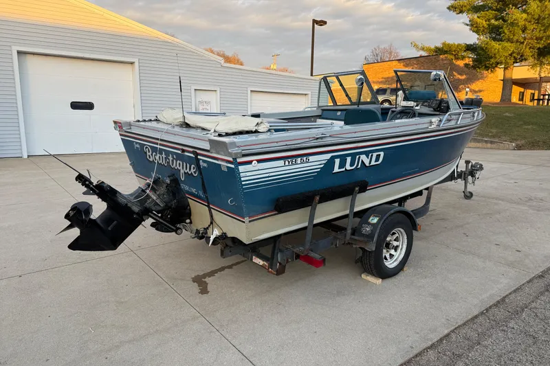 Slide: The Image of 1988 Lund Tyee 5.5 boat on trailer, parked outside a garage. - 7