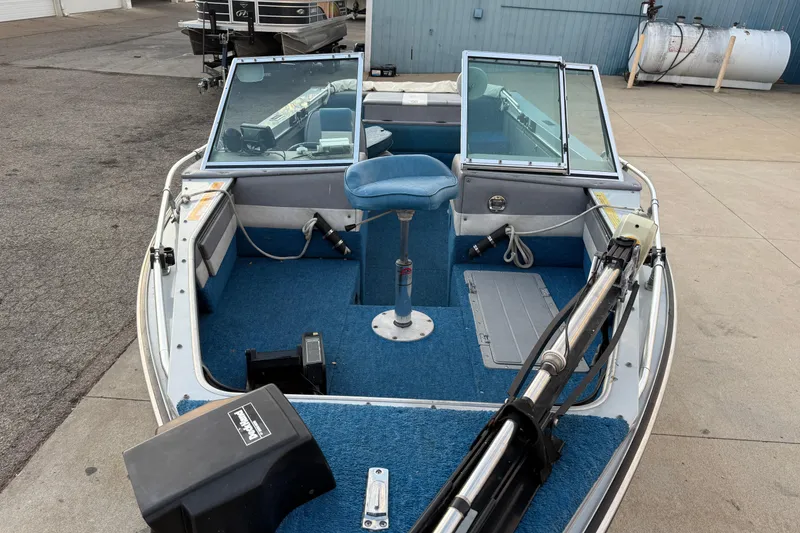 Slide: The Image of 1988 Lund boat interior with blue carpet and swivel seat, docked on concrete. - 8