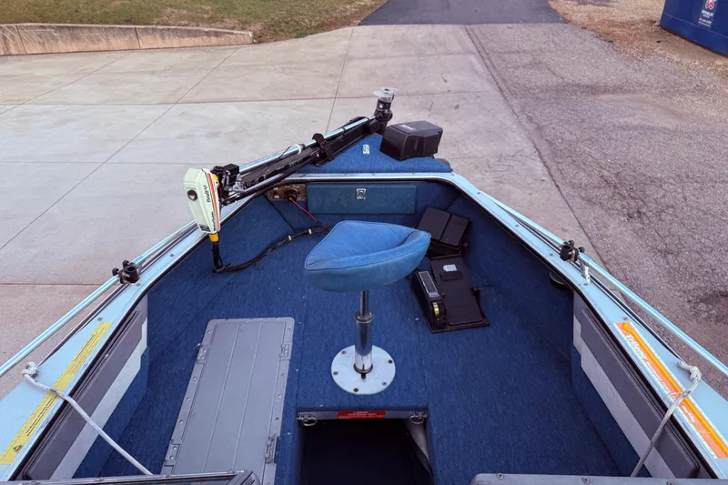 Slide: The Image of 1988 Lund boat interior with blue seat, trolling motor, and storage compartments. - 9